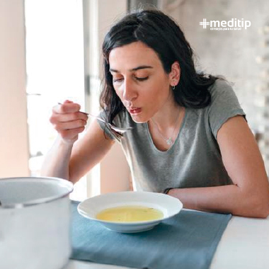 Remedios para el dolor articular: mujer con problemas de huesos y articulaciones comiendo sopa de médula
